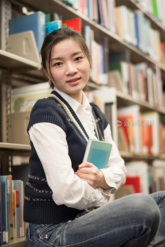 女孩在书架旁抱着一本书