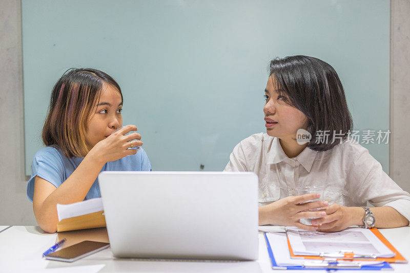 女士一边用笔记本电脑一边喝咖啡