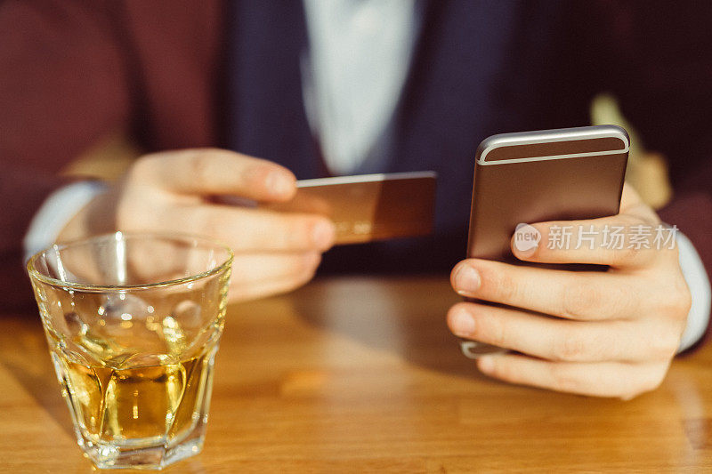 一名男子在咖啡馆用智能手机刷信用卡