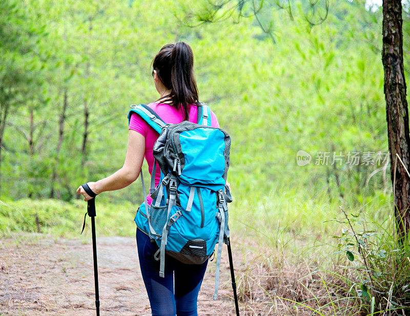 在树林里背着背包的年轻女性徒步旅行者