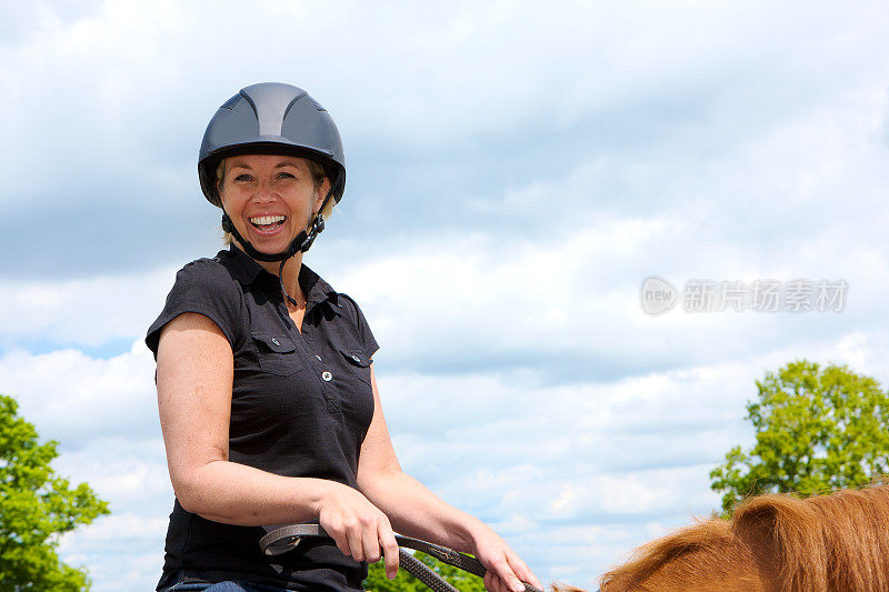 在马背上微笑的女人在户外学习骑马