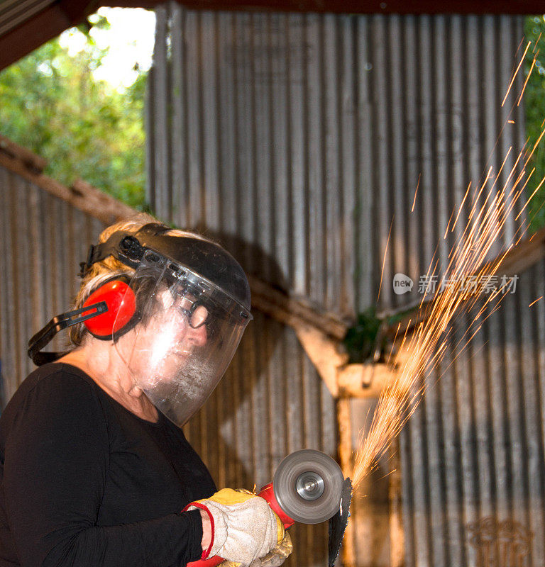 焊工-年长妇女研磨金属艺术品