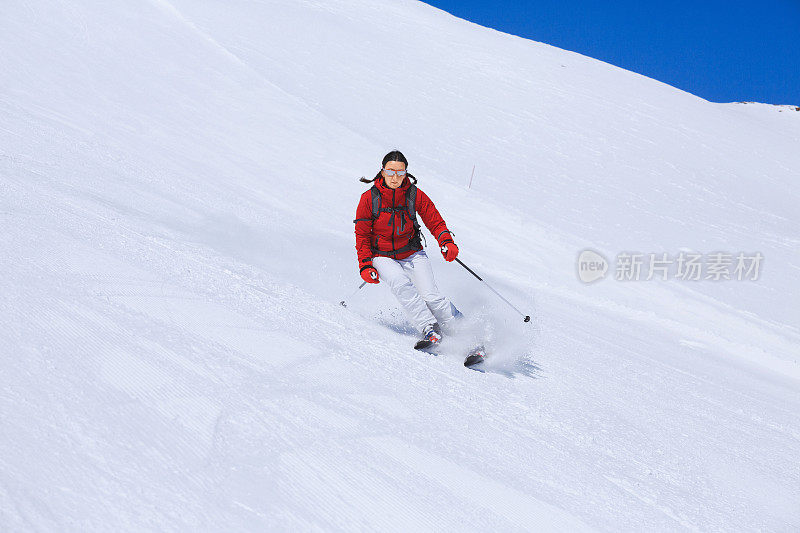 在阳光明媚的滑雪胜地滑雪的中年妇女滑雪