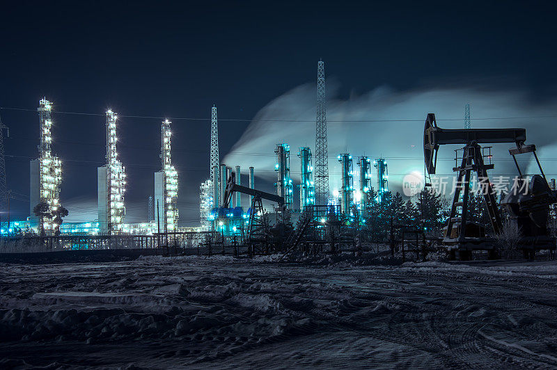 石油钻塔和明亮的工业现场在晚上。