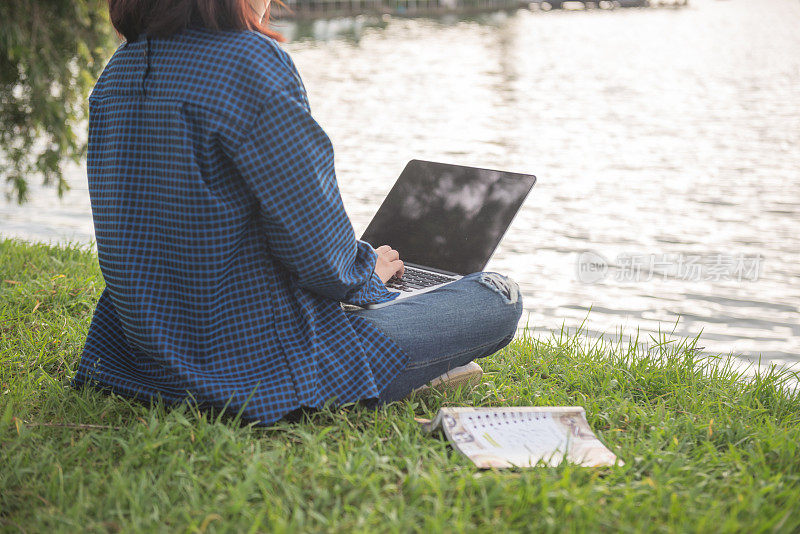 坐在湖边的草地上使用笔记本电脑