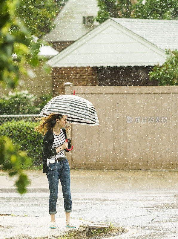 少女撑着伞在雨中走在街上。纽约皇后区