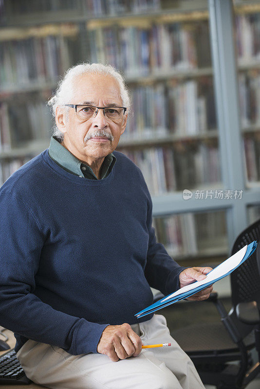 西班牙裔老人戴着眼镜，拿着文件夹