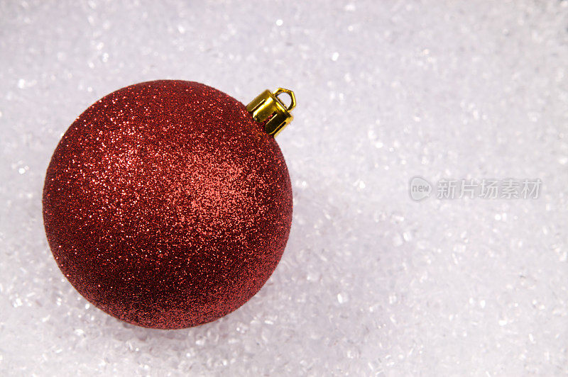 红色闪烁的圣诞装饰在白色的雪晶体