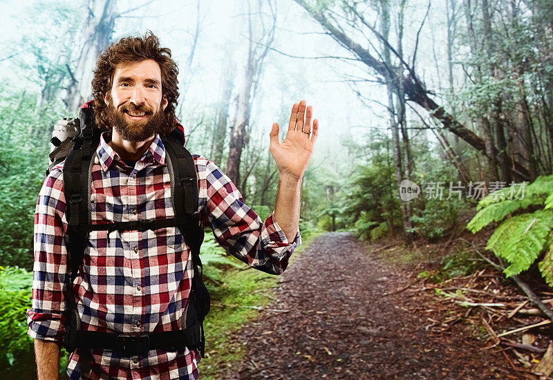 微笑的徒步旅行者在森林里挥手