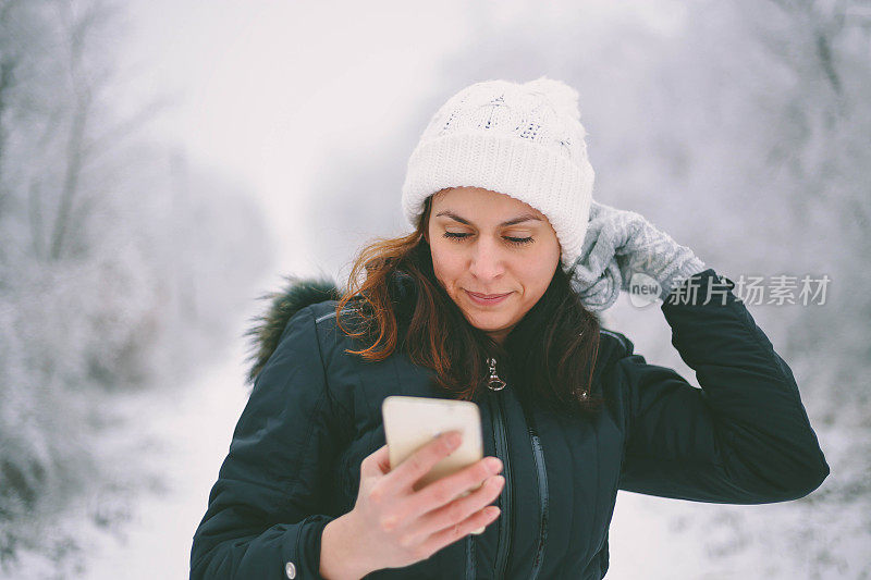 年轻美丽的黑发女子在一个下雪天打电话