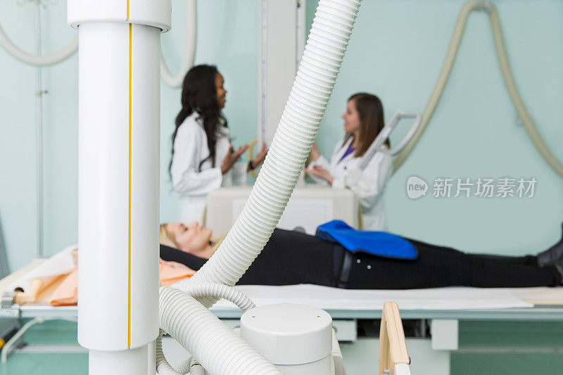 年轻女子正在做x光检查…两名放射科医生在准备检查