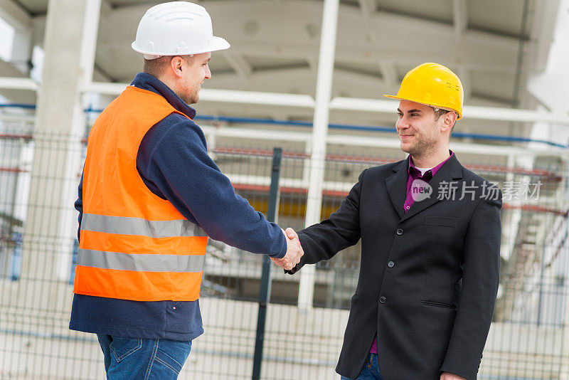 建筑师和建筑工人握手。