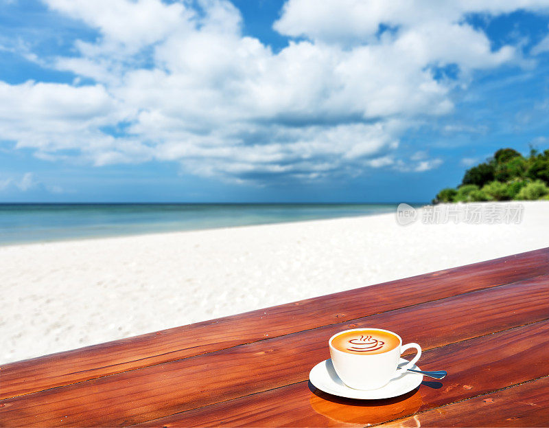 在热带海滩的木桌上，一杯咖啡