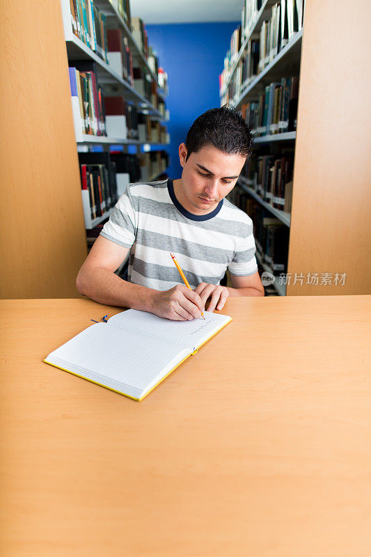 年轻帅气的大学生在图书馆做笔记