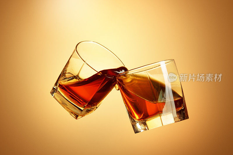 两杯威士忌在棕色杯中碰撞