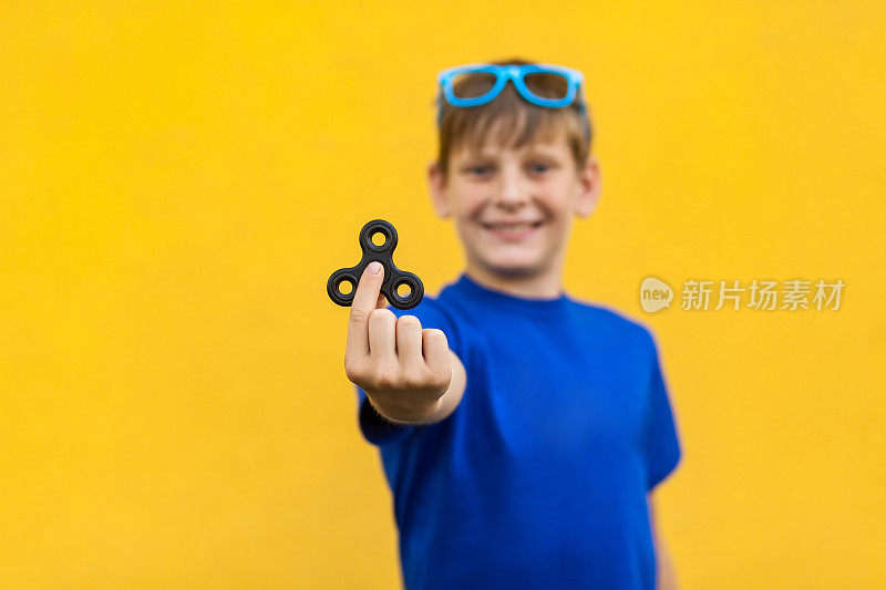 男孩与指尖陀螺在黄色背景。