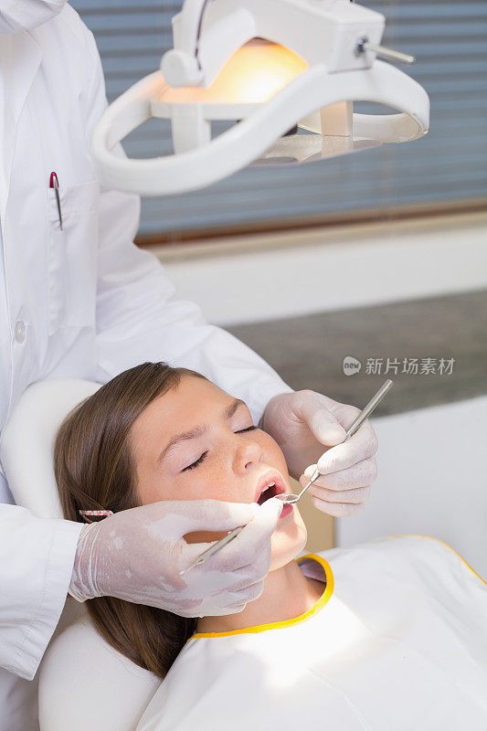儿科牙医在牙医的椅子上检查病人的牙齿