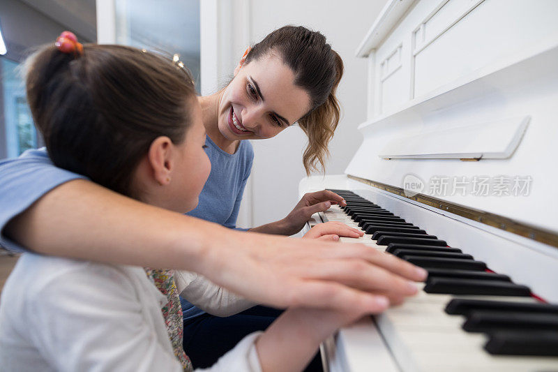 母亲帮助女儿弹钢琴