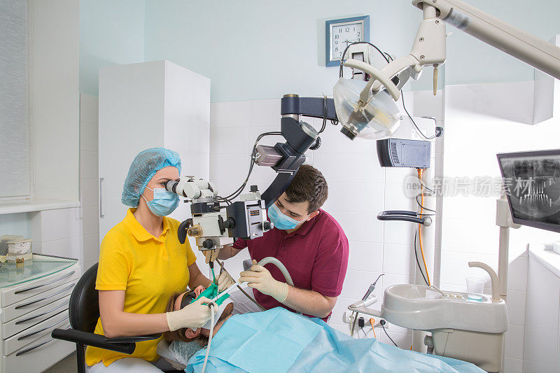 专业牙医在办公室用显微镜检查病人
