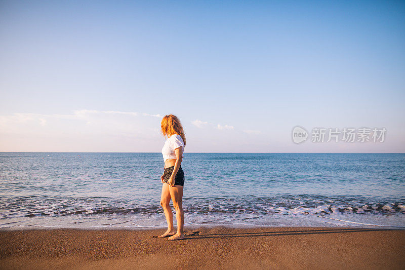 一个红发女人站在沙滩上