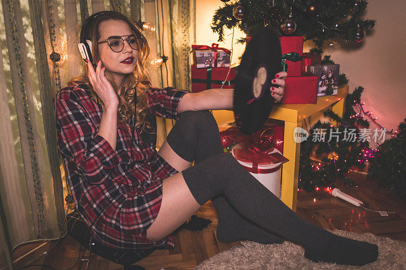 美丽的女人在圣诞节期间听黑胶唱片的音乐