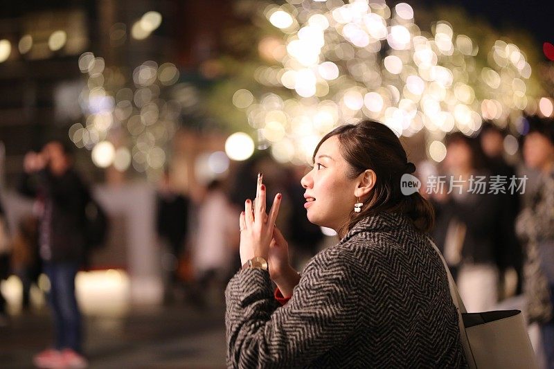 一个年轻女人在拍圣诞彩灯