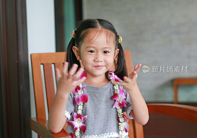 可爱的微笑小亚洲女孩与欢迎兰花花花环。