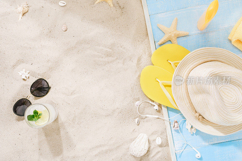 草帽，太阳镜，人字拖，鸡尾酒，带拷贝空间的防晒霜。沙上的旅行者配件。旅游度假的概念。夏天的背景