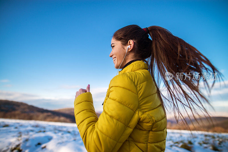 近距离观看快乐迷人勤劳活跃的健身女孩马尾辫在冬季运动服慢跑在大自然外面。