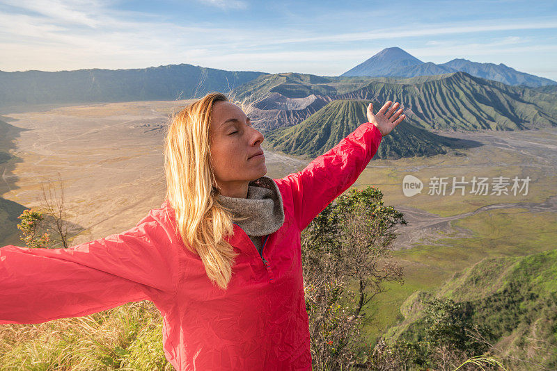 年轻的女人徒步旅行在印度尼西亚的Bromo火山上伸出双臂-人们旅行有趣的冒险概念成功和成就