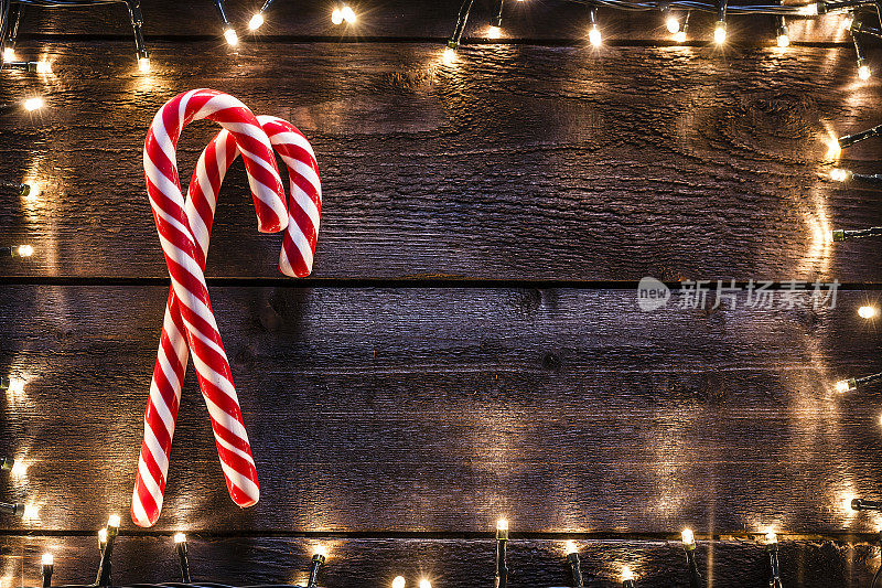 圣诞背景:两根拐杖糖放在质朴的木桌上