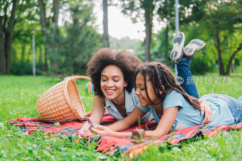 快乐的女孩在野餐时使用手机