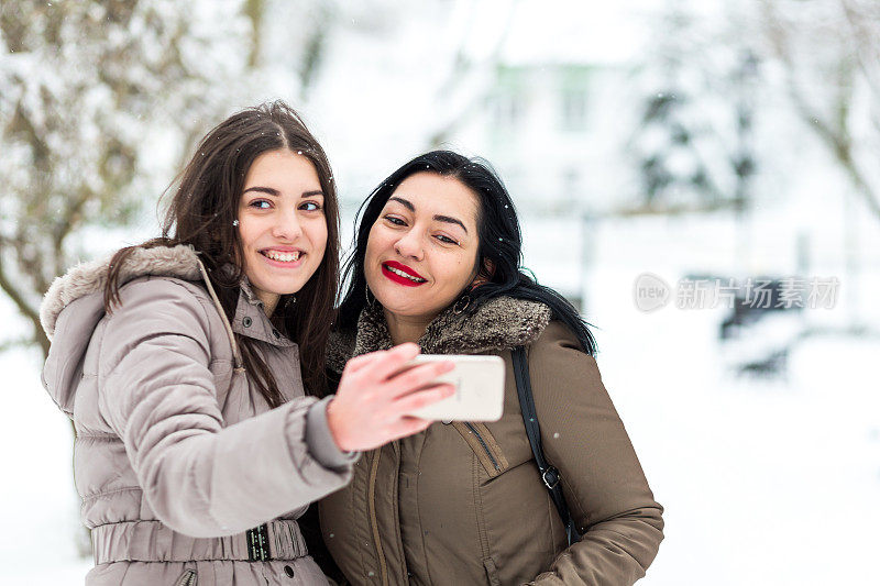 快乐的母女在雪中自拍