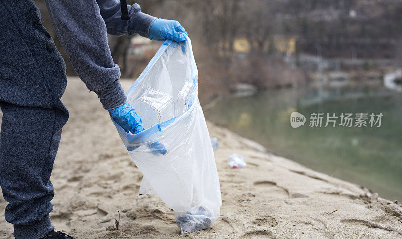 一名年轻人在河边捡塑料瓶