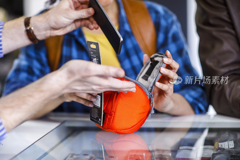 把手机放在商店展示柜上的一个橙色小钱包里