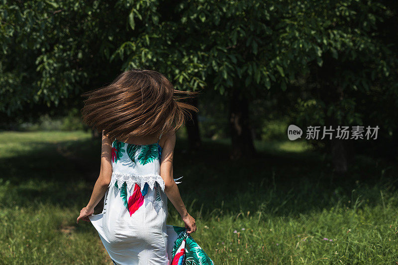 在阳光明媚的夏日里，年轻女子在草地上奔跑