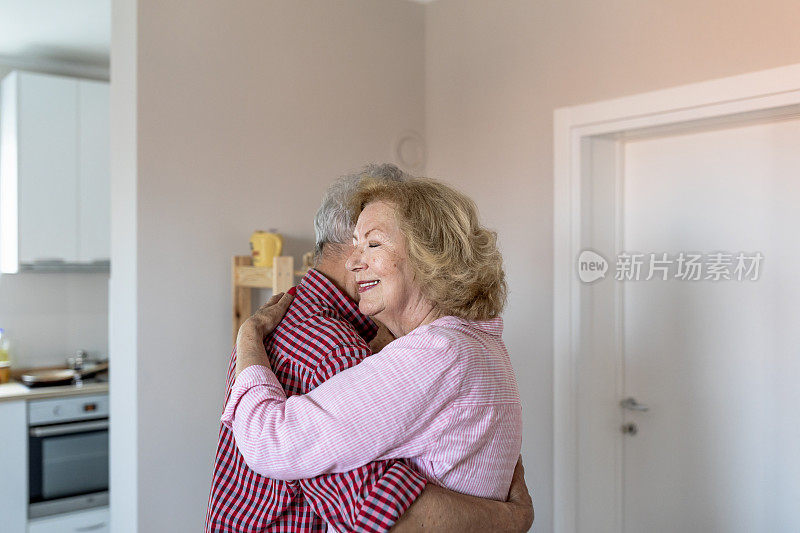 快乐的老夫妇跳着华尔兹，微笑着。快乐的老年夫妻在家里跳舞。