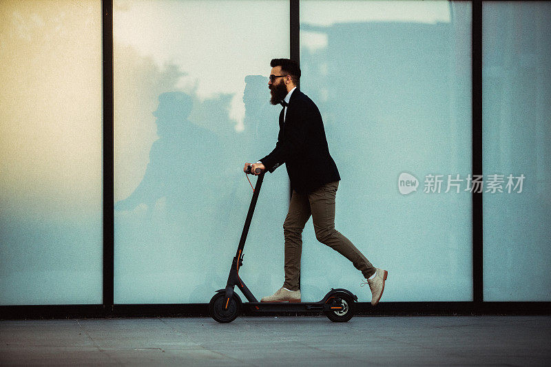 赶时髦的商人在城市里骑着滑板车