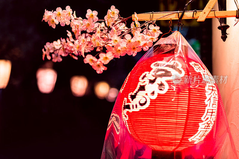 日本京都祗园区的街道上，夜晚灯火通明的纸灯笼和樱花