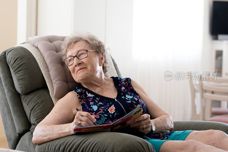 老女人在最喜欢的椅子上做填字游戏