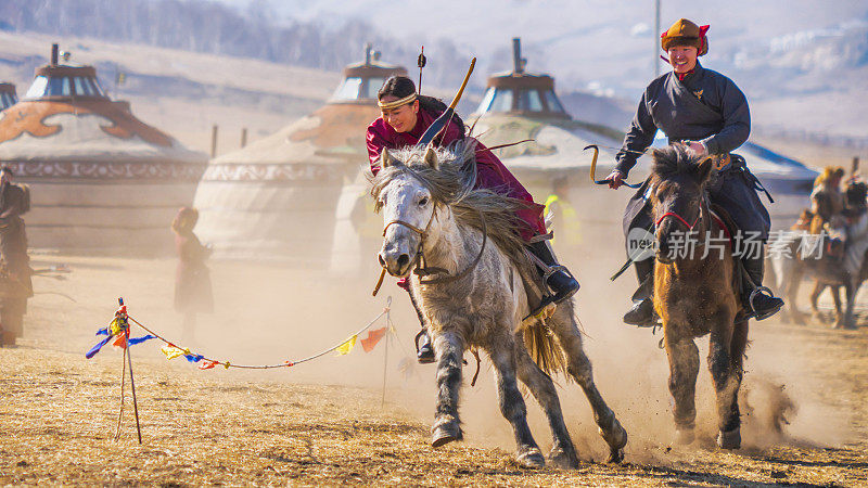 穿着传统服饰骑马的蒙古人来自蒙古国的蒙古村。与风景秀丽的蒙古山。