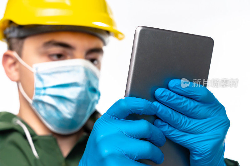 年轻的工程师或工人与N95口罩和手术手套使用数字平板在白色背景，特写