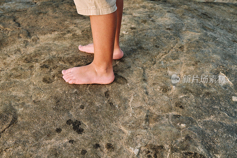 赤裸着脚踩在岩石上的孩子