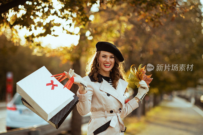微笑的时尚女性与购物袋和秋叶