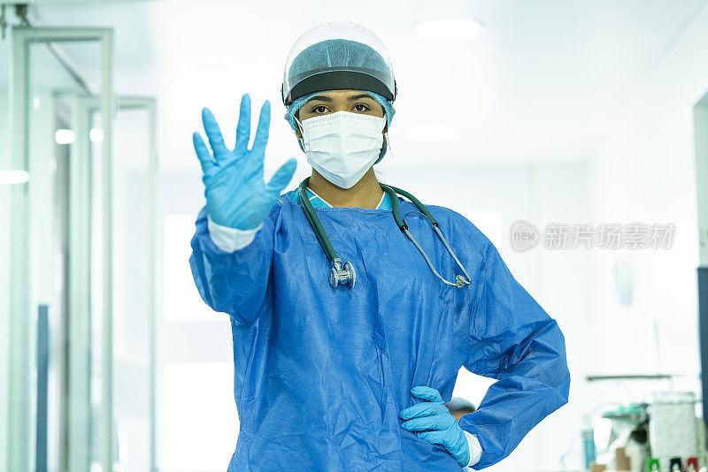 在重症监护室医院，身穿生物安全服的医生在镜头前用手指着手势