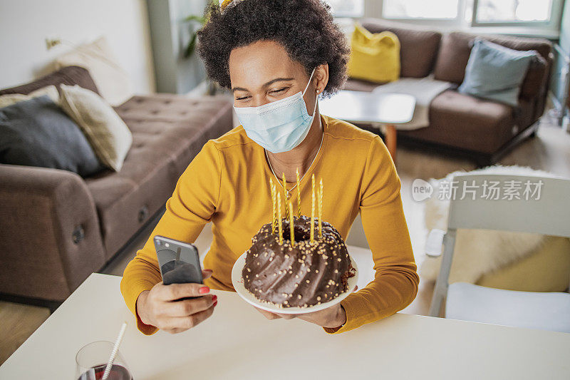 非洲妇女戴着面具通过手机视频电话庆祝生日