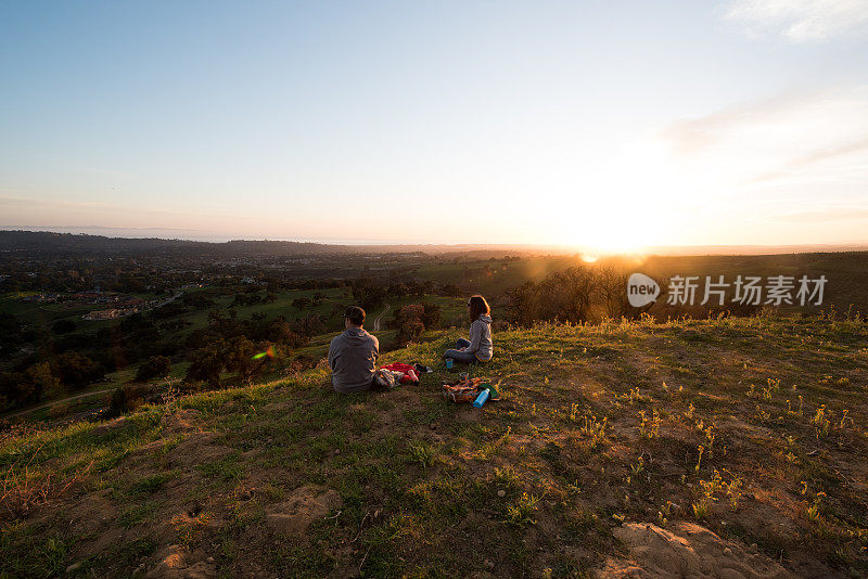 夫妻在日落时欣赏山和海的景色