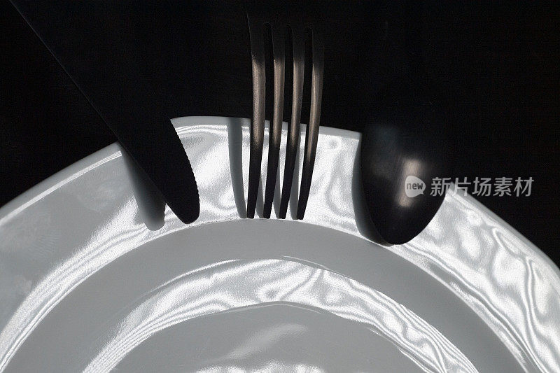 一个白瓷盘子，一把餐刀，一把叉子和一把勺子