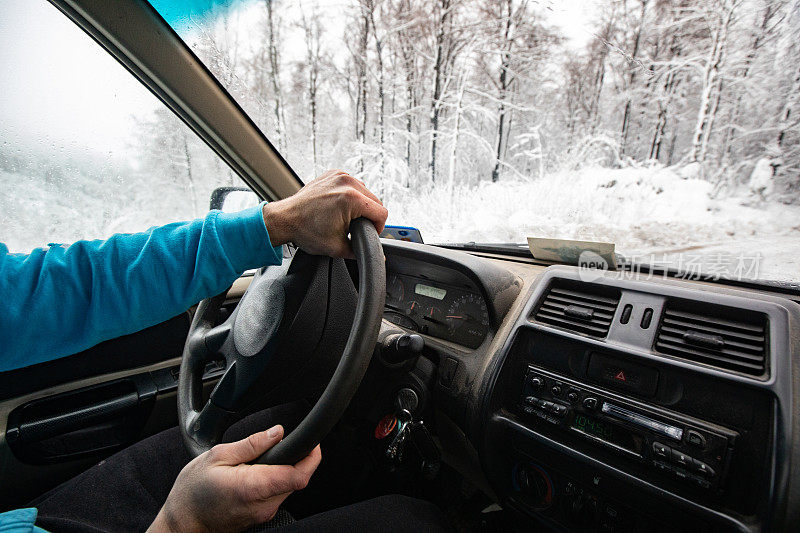 一名成年男子在冬天滑的乡村道路上开车