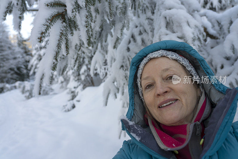 成熟的女人穿着皮大衣在冬天的森林里自拍